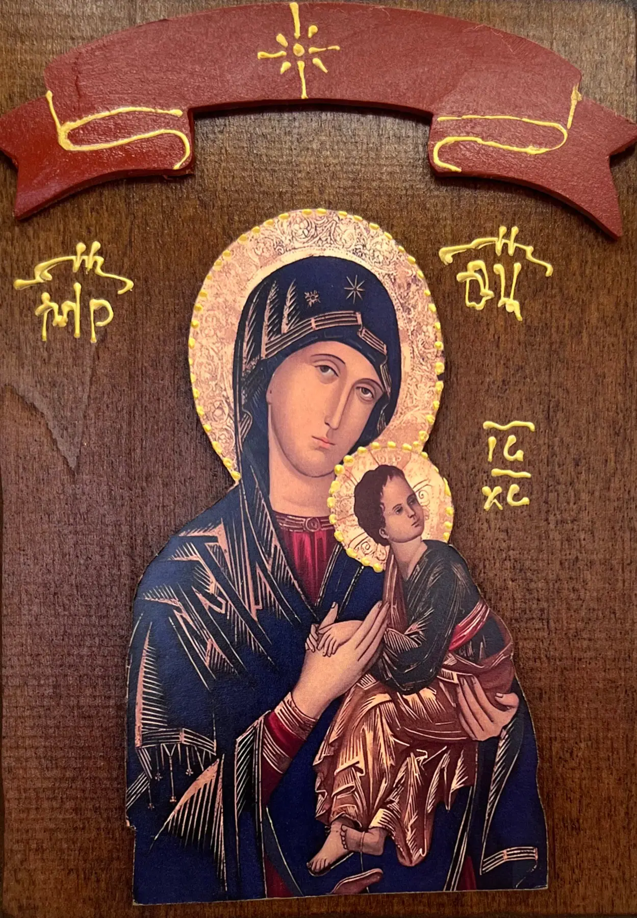Drvena ikona Presvete Bogorodice Stradalne (Strasne) - Bogorodica u tamnoplavom maforiju drži malog Hrista koji je hvata za ruku, zlatni reljefni oreoli, monogrami ΜΡ ΘΥ i IC XC, crvena traka na drvenoj dasci