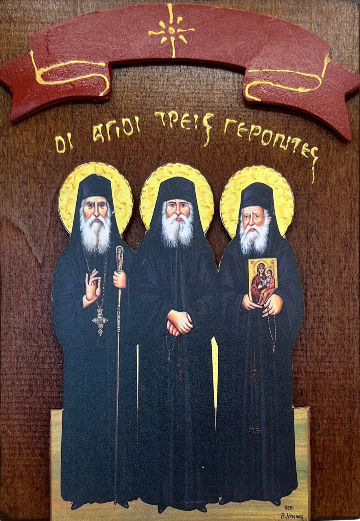 Drvena ikona tri sveta starca - Sveti Jakov Calikis, Sveti Pajsije Svetogorac i Sveti Porfirije Kavsokalivit u crnim monaškim odeždama, natpis ΟΙ ΑΓΙΟΙ ΤΡΕΙΣ ΓΕΡΟΝΤΕΣ, crvena traka na drvenoj dasci