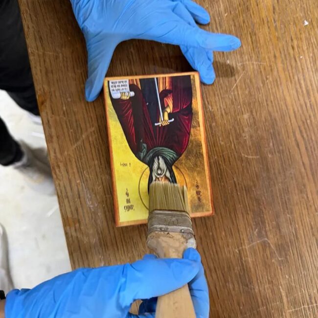 Nanošenje zaštitnog sloja laka na gotovu ikonu širokom četkom radi dugovečnosti.